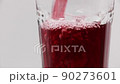 Pour pomegranate juice into a rotating glass on a white background. 90273601