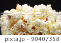 Pour Popcorn into a rotating glass on a Black background. 90407358