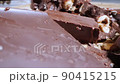extreme close-up detailed broken pieces of bittersweet chocolate with whole hazelnuts 90415215