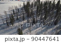 Aerial view of Winter Forest Nature Snow Covered Trees. Ice road exploring local landscapes, buildings on area surrounded by beautiful coniferous Siberia forest 90447641