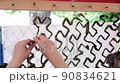 Womens hands weaving camouflage net for army, volunteers make camouflage protection for military needs, selective focus 90834621