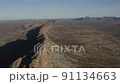 Aerial, drone, wide shot of a very long, narrow, steep, ridgeline, separate from the other mountains in the range, and flanked by two large plains 91134663