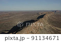 Aerial, drone wide shot of a very long, narrow, sharp ridge line, flanked on either side by an expansive plain, stretching off toward the horizon 91134671