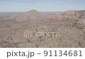 Drone view from high up showing wide, expansive view of a dry, dusty mountain range and valleys below 91134681