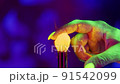 Glowing Neon UV Powder on a Makeup Brush Flying Away with Woman Finger Flicking on Neon Background 91542099