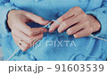 close up the woman's hands knitting a blue woolen sweater 91603539
