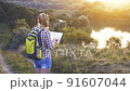 woman tourist with a map and a backpack on a hike navigates the terrain. Leisure 91607044