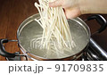 沸騰した鍋にうどんの麺を入れるところ 91709835