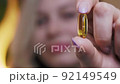 A young beautiful woman holds a capsule of medicine in her hand, macro shot, blurred background 92149549