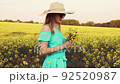 Young woman standing on the rape field with sunrise on the background 92520987