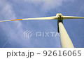 Bottom closeup detail view new white modern wind turbine farm power generation station against plane flying clear blue sky. Clean sustainable zero emission alternative electricity windfarm industry 92616065