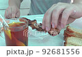 person's hands, burning themselves, carefully remove hot pieces of shish kebab meat from a skewer 92681556