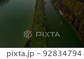 A man rowing bot on a body of water surrounded by trees 92834794