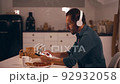Man working at night on his kitchen using tablet and listen to music with headphones 92932058