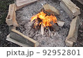 a small campfire and new wooden logs laying around the fire 92952801
