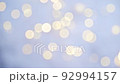 Glowing bokeh flickering on a blue background. Christmas light, magic, glitter, celebration. A universal beautiful background with blur in gentle colors for websites, designers. 92994157
