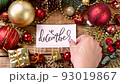 Woman's hand putting a Christmas card with the text DECEMBER on a wooden table 93019867