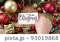 Woman's hand putting card with the text CHRISTMAS on a wooden table 93019868