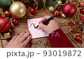 Woman's hand writing JANUARY on a card on the wooden table with Christmas decorations around close up 93019872