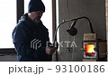 Blacksmith forges and checking tempered metal horseshoe in jar with water at forge. 93100186