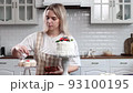 Pastry chef confectioner young caucasian woman decorate cake on kitchen table. Cakes cupcakes and sweet dessert 93100195