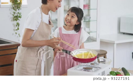 キッチンでママと一緒に卵焼きを作る小学生の女の子の動画素材