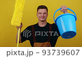 A young man in uniform holds a bucket of water and a mop in his hands. Janitor cleans and disinfects the space 93739607