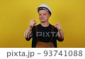 A friendly young worker in a helmet and clothes of a worker of Caucasian appearance shows a gesture - "Call me"" 93741088