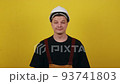 Foremans salary. Close-up photo of a happy young man in a suit and construction helmet, who is holding a wad of cash in his right hand and showing thumbs up. 93741803
