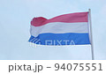 Flag of the Netherlands waving in wind on blue sky background, closeup 94075551
