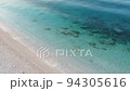 Drone view of beautiful footage while turquoise sea waves breaking on the coastline. Aerial shot of beach meeting deep blue sea water and foamy waves. 94305616