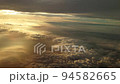 夕日に染まる日没直前の雲上を飛ぶ飛行機からの幻想的な光の風景 94582665