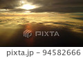夕日に染まる日没直前の雲上を飛ぶ飛行機からの幻想的な光の風景 94582666