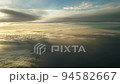 夕日に染まる日没直前の雲上を飛ぶ飛行機からの幻想的な光の風景 94582667