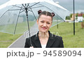 A woman in a black jacket under a transparent umbrella, on the street of the city, outdoors. Rain. 94589094