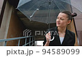 A woman in a black jacket under a transparent umbrella, on the street of the city, outdoors. Rain. 94589099