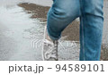 A woman in a black jacket under a transparent umbrella, on the street of the city, outdoors. Rain. 94589101