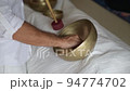 A hand moving a wooden stick along a border of a tibetan singing bowl during healing sound therapy A hand moving a wooden stick along a border of a tibetan singing bowl during healing sound therapy 94774702