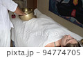 A man wearing in white doing healing sound massage with tibetan singing bowl to a young woman indoor A man wearing in white doing healing sound massage with tibetan singing bowl to a young woman indoor 94774705
