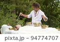 A man wearing in white doing healing sound massage with tibetan singing bowl to a young woman A man wearing in white doing healing sound massage with tibetan singing bowl to a young woman 94774707