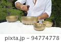 A hand moving a wooden stick along a border of a tibetan singing bowl during healing sound therapy A hand moving a wooden stick along a border of a tibetan singing bowl during healing sound therapy 94774778