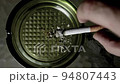 Hand picks up cigarette to smoke and puts it back on ashtray 94807443