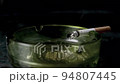 Lit cigarette burning in ashtray close up 94807445