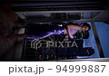 rich woman in a purple dress standing by the window with a glass of champagne and looks at the night city with skyscrapers. vertical 94999887