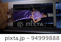 rich woman in a purple dress standing by the window and looks at the night city with skyscrapers. vertical 94999888