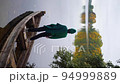 a woman in a green sweater, hat and sunglasses stands on an old wooden boat by the lake in autumn in the village. Vertical 94999889