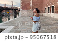 one person, a woman 30 years old in a blue top. she is looking at map navigator app in smartphone. her walks in venice italy 95067518