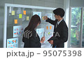 Businessman and Businesswoman is writing and brainstorming on glass board. 95075398