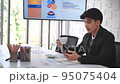Office man is drinking coffee using mobile while relaxing having a break in meeting room. 95075404