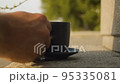 Hand putting cup of coffee on a granite parapet 95335081